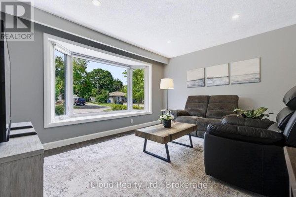 Living room with gray walls, a large bay window, and dark furniture. - 93 Church Street, Orangeville
