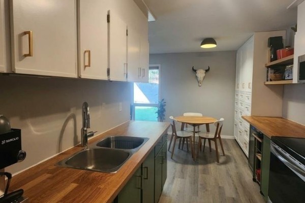 Kitchen counter with stainless steel sink and wooden countertop, looking towards dining area. - 93 Deerborne Drive Unit# 102, Elkford
