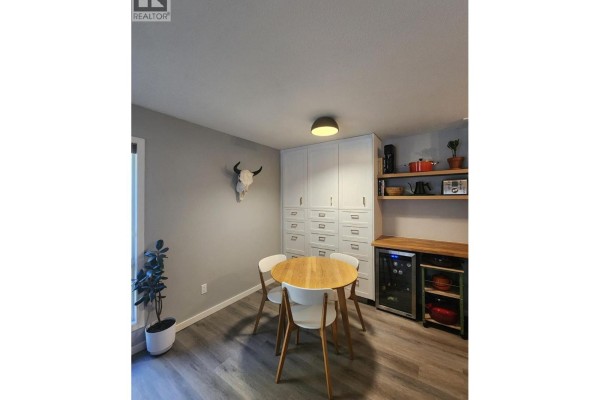 Dining area with a round table and chairs, next to a wall of storage cabinets. - 93 Deerborne Drive Unit# 102, Elkford