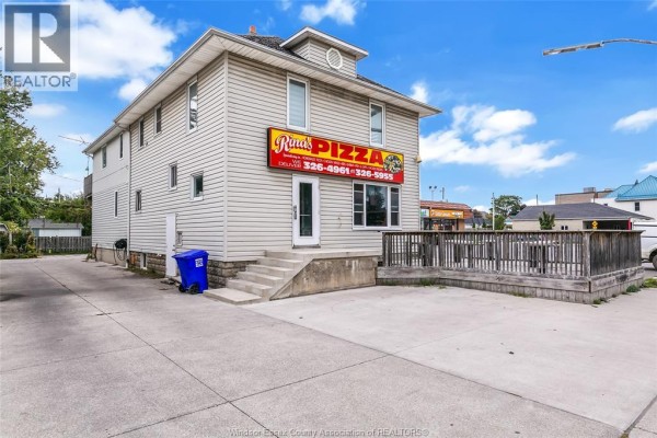 Side view of the commercial building showing stairs, outdoor seating area, and alley access. - 93 Erie Street South, Leamington
