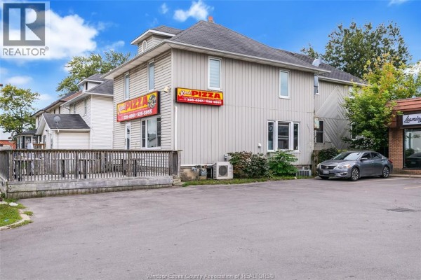 Rear view of the commercial building with outdoor seating, air conditioning units, and parking area. - 93 Erie Street South, Leamington