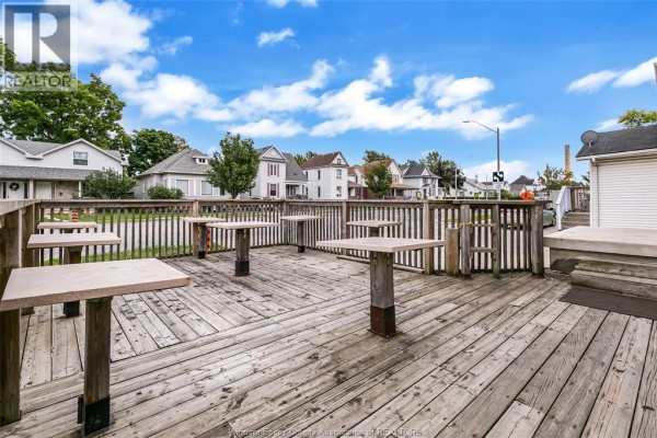 Wooden deck with square tables and benches, overlooking residential houses. - 93 Erie Street South, Leamington