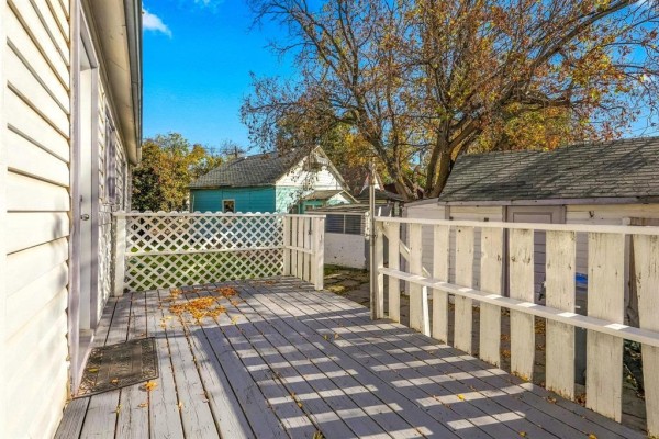Wooden deck with a white railing and lattice work, overlooking a backyard. - 93 Gateway Road, Winnipeg
