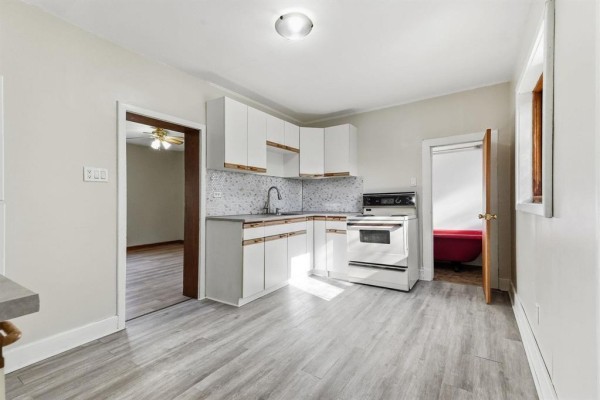 White kitchen with grey laminate flooring, white cabinets, and a white stove. - 93 Gateway Road, Winnipeg