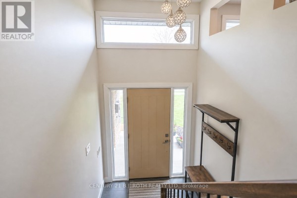 View from above looking down at the foyer with a beige door, a coat rack, and modern pendant lights. - 93 Grove Street E, Barrie