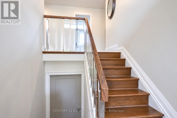 Wooden staircase with white railings and a unique glass partition leading to the upper level. - 93 Grove Street E, Barrie