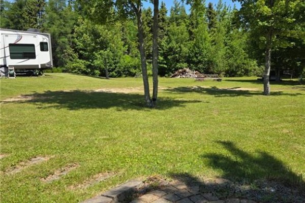 Overhead view of a grassy area with trees, showing a small shed in the upper right corner. - 93 Poirier Street, Grande Digue