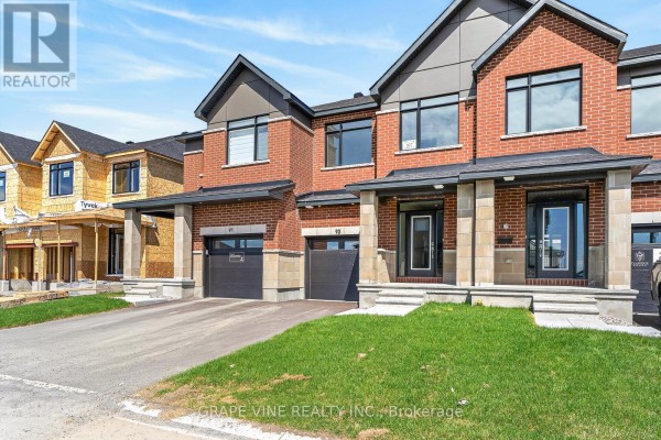 Exterior front view of townhouses, with one unit under construction on the left, red brick and grey accents. - 93 San Felice Circle, Ottawa