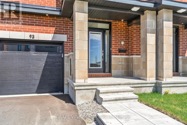 Close-up view of a townhouse entrance with a glass door, concrete steps, and a dark garage door. - 93 San Felice Circle, Ottawa