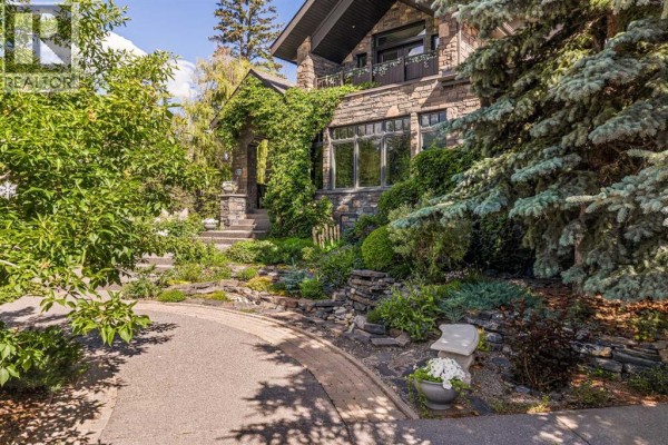 Entryway with wood floor, red door, stone archway, and view into living room. - 930 9 Street S, Canmore
