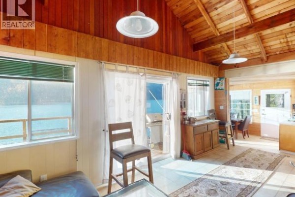 Interior living area with wood-paneled walls and ceiling, large windows, and a view of the lake. - 9302 Powell Lake, Powell River