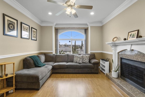 Another angle of the living room highlighting the fireplace and large window. - 9309 134 Street, Surrey