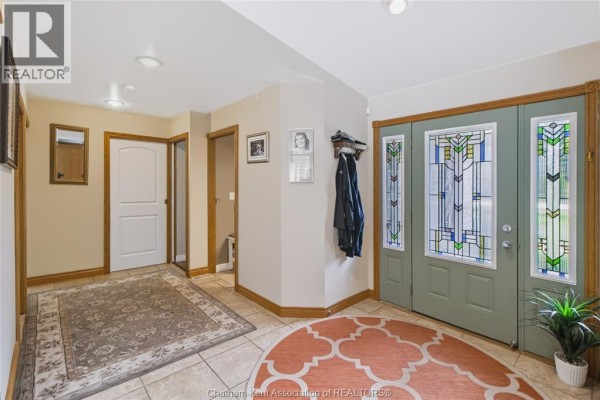 Foyer with tiled floor, decorative rugs, wood trim, and stained glass front doors. - 931 Charing Cross Road, Chatham