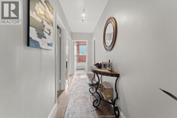 Hallway with light grey walls, dark wood floors, and a console table with a mirror. - 931 Lillian Avenue, Windsor