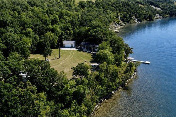 Aerial view of a property on Pelican Lake featuring a mobile home, garage, and dock. - 93100 25n Road, Pelican Lake
