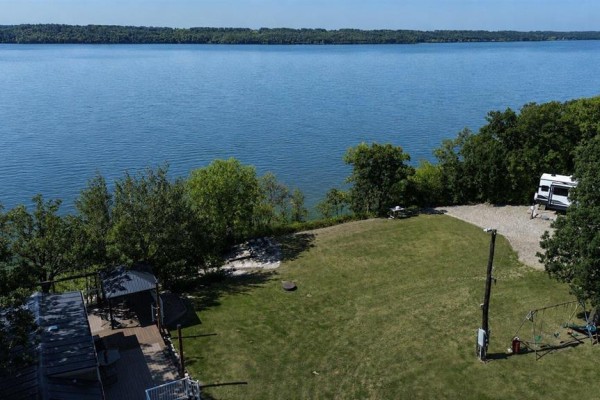 View from above of a grassy yard with a mobile home, RV, and large lake in background. - 93100 25n Road, Pelican Lake