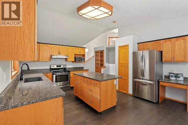 Modern kitchen with light wood cabinets, granite countertops, and stainless steel appliances. - 9323 69a Avenue, Grande Prairie