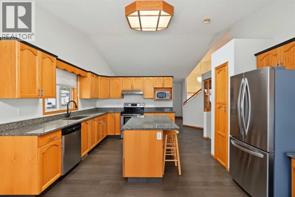 Spacious kitchen with light wood cabinets, granite countertops, and a central island. - 9323 69a Avenue, Grande Prairie