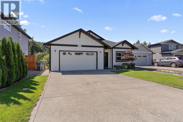 Rear exterior of a white two-story house with a deck and a grassy backyard. - 933 Blakeon Pl, Langford