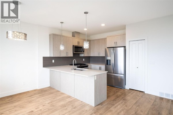 Modern kitchen with island, stainless steel appliances, and pendant lighting - 933 Mt Robson Place Unit# 55, Vernon