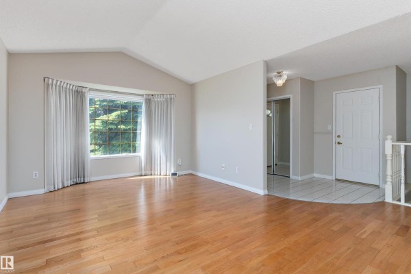 Interior foyer with white tile flooring, white trim, a white door, and wood floors. - 933 Youville Dr W Nw, Edmonton