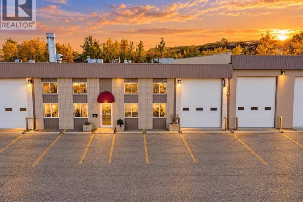 Commercial building front with garage doors and windows under sunset sky. - 933a 48 Avenue Se, Calgary