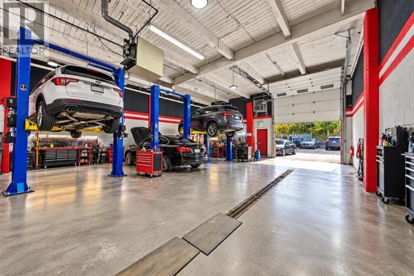 Car repair shop interior with two cars on lifts and tool chests. - 933a 48 Avenue Se, Calgary