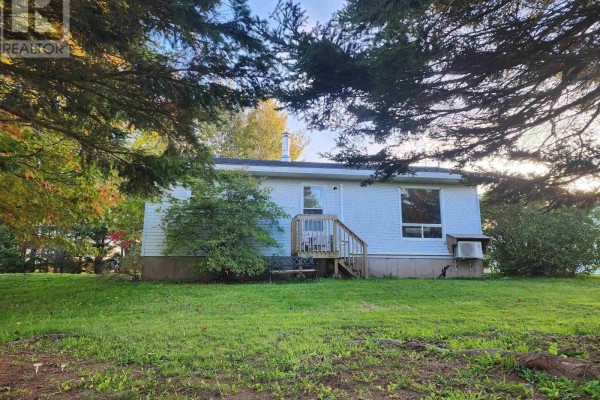 Exterior of a white bungalow with a small wooden deck and a window air conditioner. - 9340 Highway 366, Port Howe
