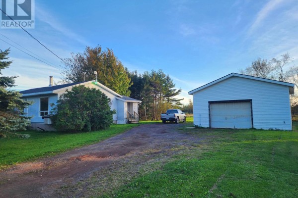 Side view of a white bungalow and a detached white garage with a gravel driveway. - 9340 Highway 366, Port Howe