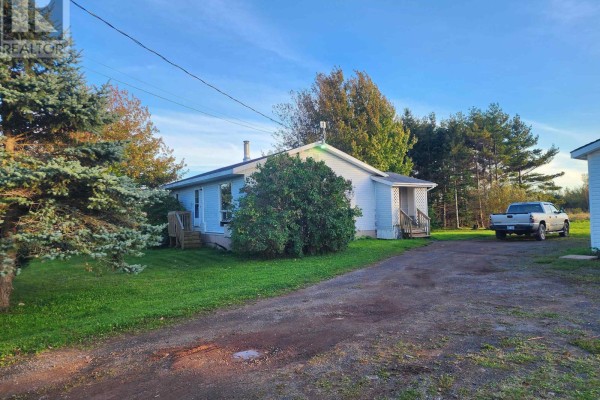 A white bungalow with a side entrance and a detached white garage on a rural property. - 9340 Highway 366, Port Howe