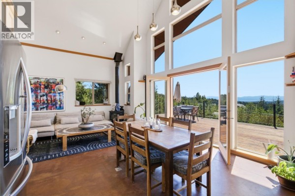 Dining area facing large windows and glass doors showing a deck and distant view of trees and sky. - 9340 Stephens Way, Halfmoon Bay
