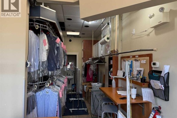 Dry cleaning racks and storage shelves fill the back room of the establishment. - 935 General Avenue Ne, Calgary