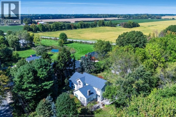 Exterior view of a light-colored house with a grey roof, surrounded by green trees and lawn. - 936 Twin Gables Drive, Harrow