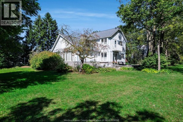 Interior foyer with a blue floral couch, wooden staircase, and hardwood floors. - 936 Twin Gables Drive, Harrow