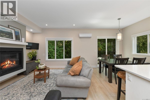Living room and dining area with grey sofa, dark wood table, and sliding glass doors. - 937 Echo Valley Pl, Langford
