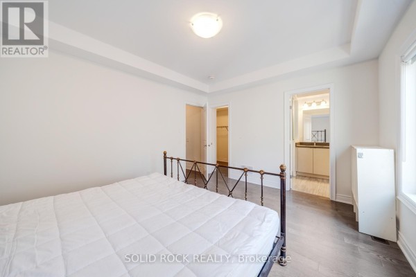 Bedroom with a metal-framed bed, a closet, and an ensuite bathroom entrance. - 9376 Bayview Avenue, Richmond Hill