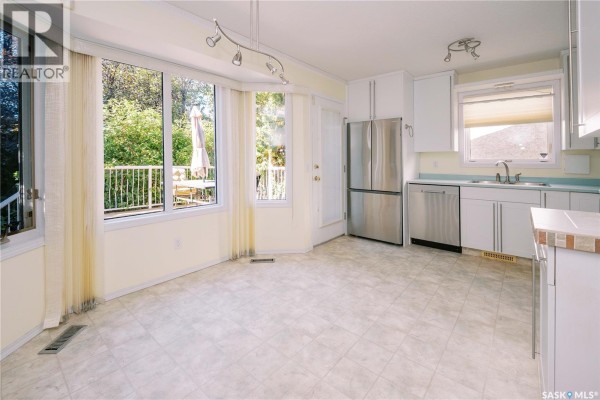 White kitchen cabinets with stainless steel handles, a white refrigerator, and a white dishwasher. - 939 Haslam Crescent, Saskatoon