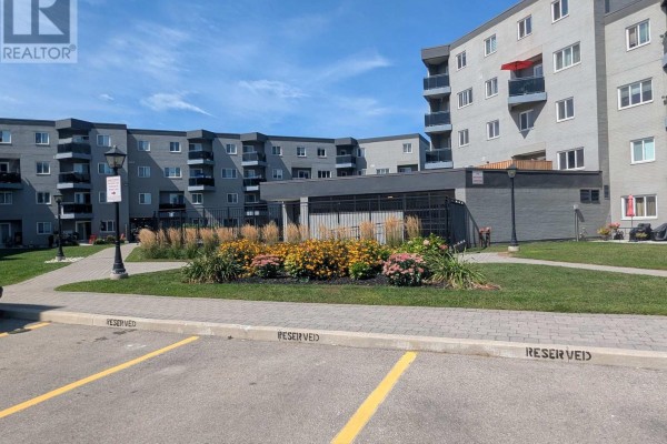 Courtyard view of apartment building with landscaping, paved walkways, and reserved parking spaces. - 94 - 2001 Bonnymede Drive, Mississauga