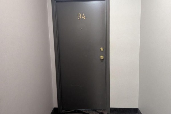 Close-up of a dark grey entrance door with brass numbering "94" and a brass doorknob. - 94 - 2001 Bonnymede Drive, Mississauga