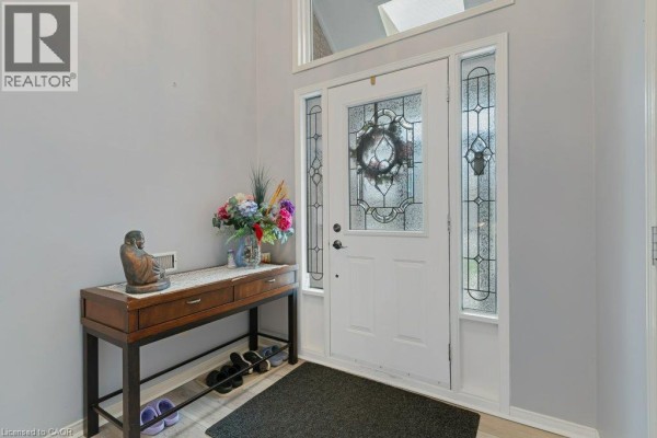 Interior view of the front door with stained glass sidelights and a console table. - 94 Dawn Crescent, Cambridge
