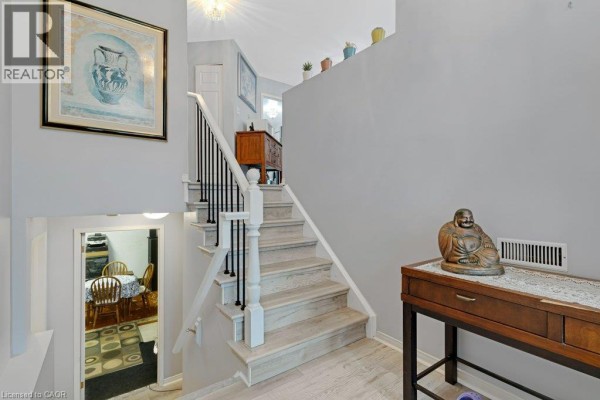 Interior staircase with light wood steps, black railings, and artwork on the wall. - 94 Dawn Crescent, Cambridge
