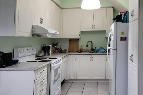 Kitchen with white cabinets, speckled countertops, white appliances, and light green walls. - 94 Forestwood Street, Richmond Hill