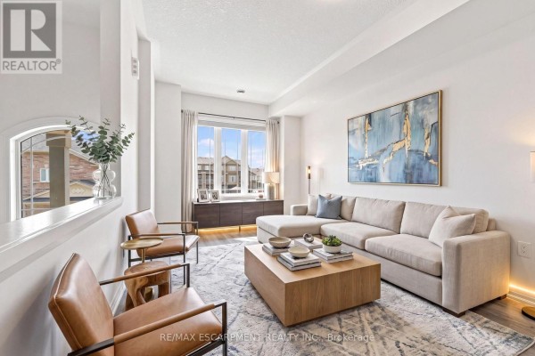 Furnished living room with a sectional sofa, two chairs, a coffee table, and a large abstract painting. - 94 Laguna Village Crescent, Hamilton