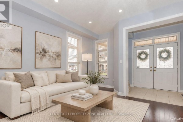 View of the front double doors and entrance from the living room with a sectional sofa and artwork. - 94 Lola Crescent, Brampton