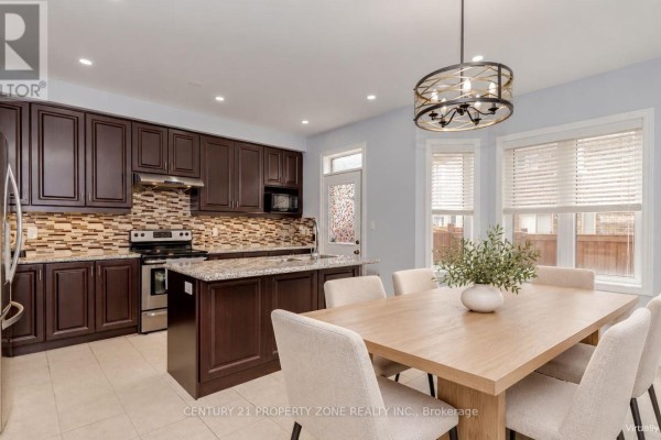 Kitchen with dark brown cabinets, granite countertops, a central island, stainless steel appliances, and a dining table. - 94 Lola Crescent, Brampton