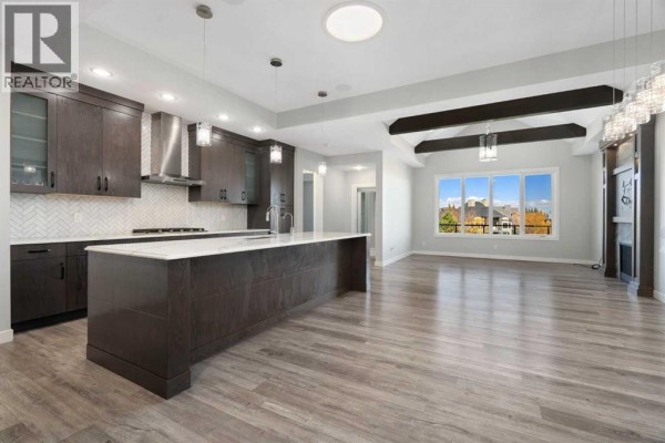 Open concept kitchen and living area with a large island, dark cabinets, and a view of the neighborhood. - 94 Mahogany Cove Se, Calgary