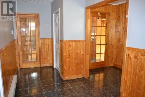 Interior hallway with dark tiled floor, wood paneled walls, and glass-paneled doors. - 94 Main Road, Aquaforte