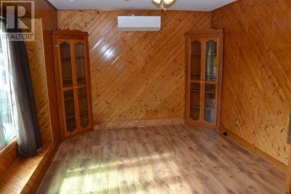 Wood-paneled room with laminate flooring, two glass-fronted display cabinets, and an air conditioner. - 94 Main Road, Aquaforte