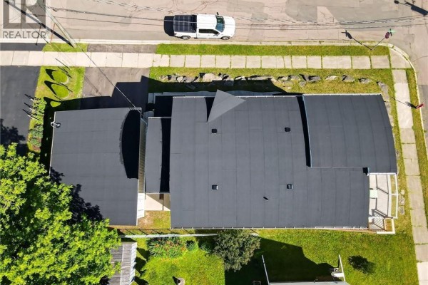 Aerial view of the property showing the dark roofs of the multi-family building and attached garage. - 94 Newton Street Unit# A&b, Moncton