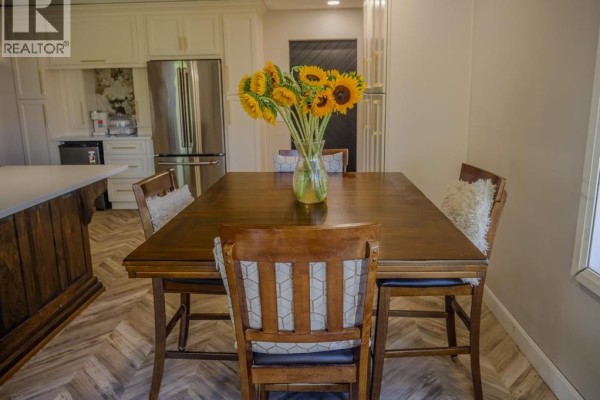 Wooden dining table and chairs in a modern kitchen with sunflowers and herringbone floors - 94 Ottawa Drive Chatham